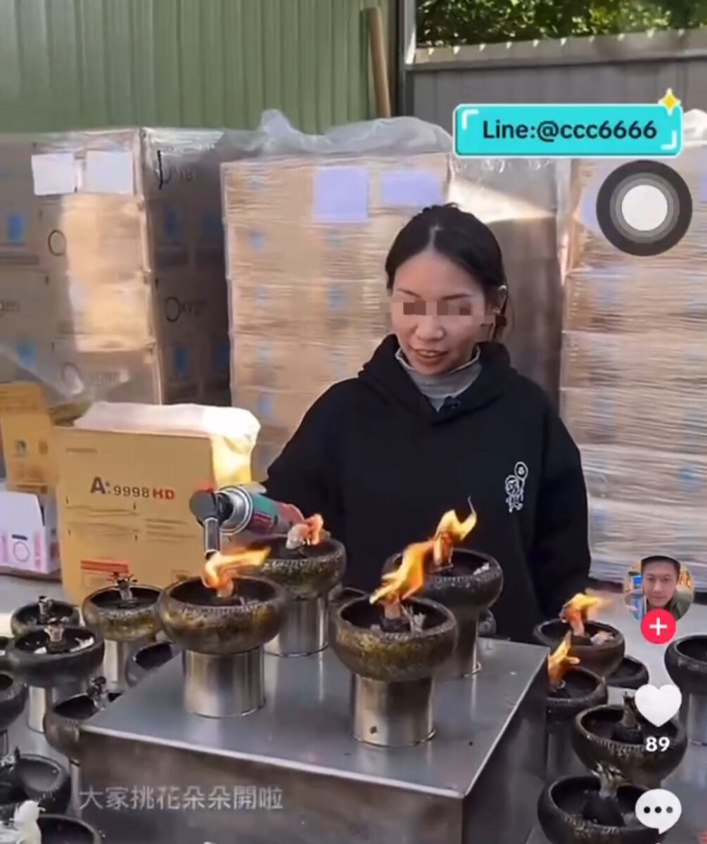 賓賓哥的員工在佛堂鐵皮屋外點燃油燈，火苗竄升之際，側邊不遠處放置著廢紙箱，只要風一吹，火舌便向易燃物即可能造成火災。(影像自社群抖音網站)。