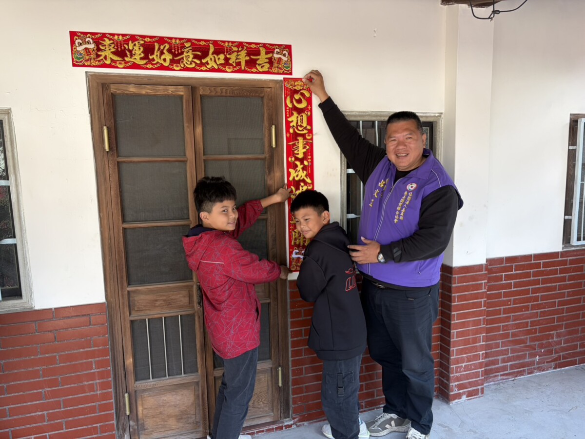 呂文正理事長帶領一起貼春聯，象徵為愛接力與心想事成。（圖/記者黃采琳攝）