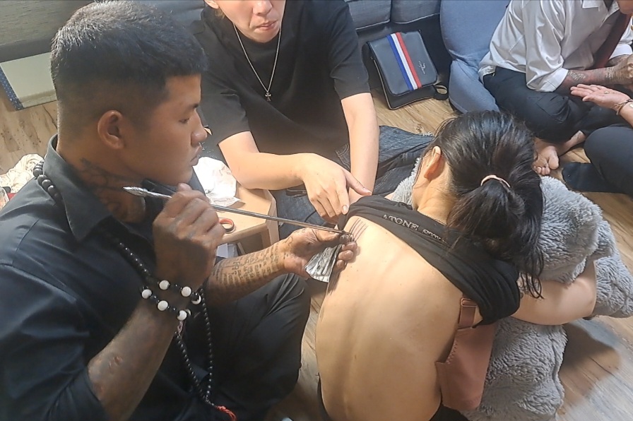 充滿神秘力量的泰國傳統「護身法刺」（Sak Yant）儀式。師父以特製金針與聖墨（含草藥、經粉與寺院聖水調製），於信眾肩頸、後背等能量要穴，依個人因緣手繪古傳護身圖騰加持。(影像由記者郭晉嘉拍攝)。