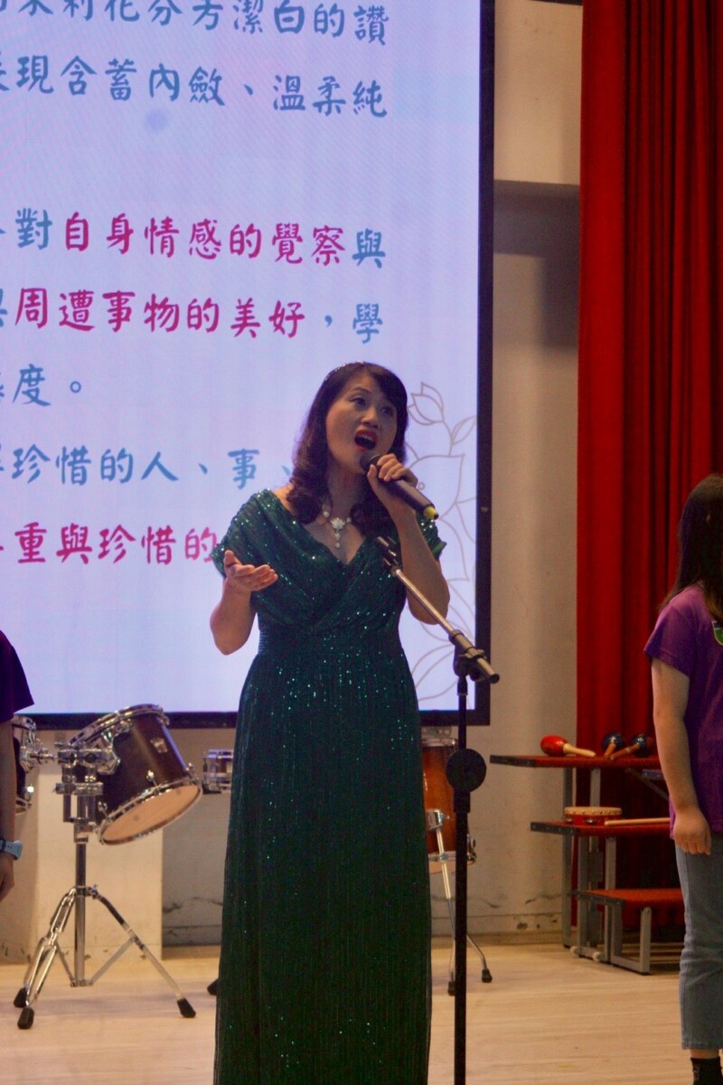 王春綢校長登台,以真誠歌聲與沉穩氣度唱出茉莉花這首名曲,展現教育者「以身示範」的力量。(影像由記者郭晉嘉拍攝)。