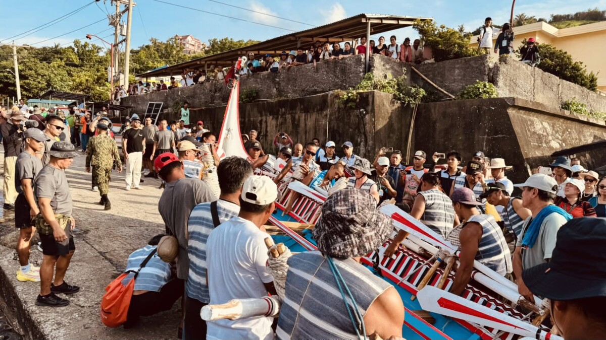 達悟族大型拼板舟靠近巴丹島港口,岸邊族人迎接(圖/原住民委員會提供)
